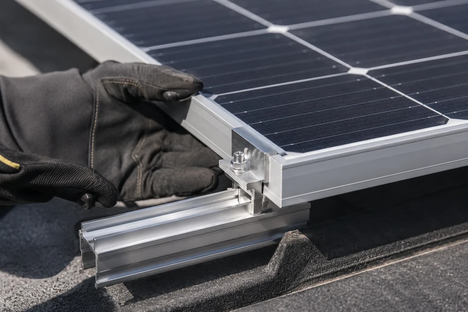 Close-up of an installer fastening a solar panel to a roof mounting rail