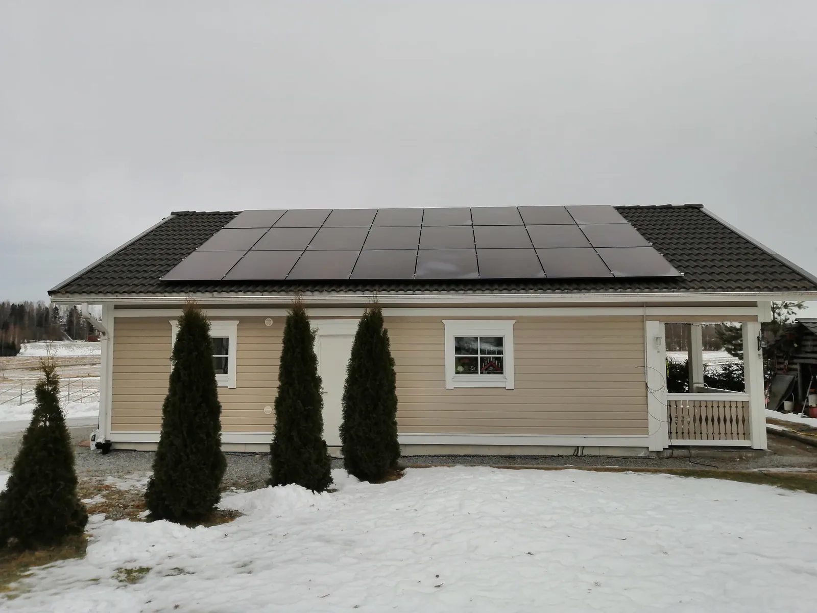 Solar panels on the roof of a light-coloured house in a winter landscape