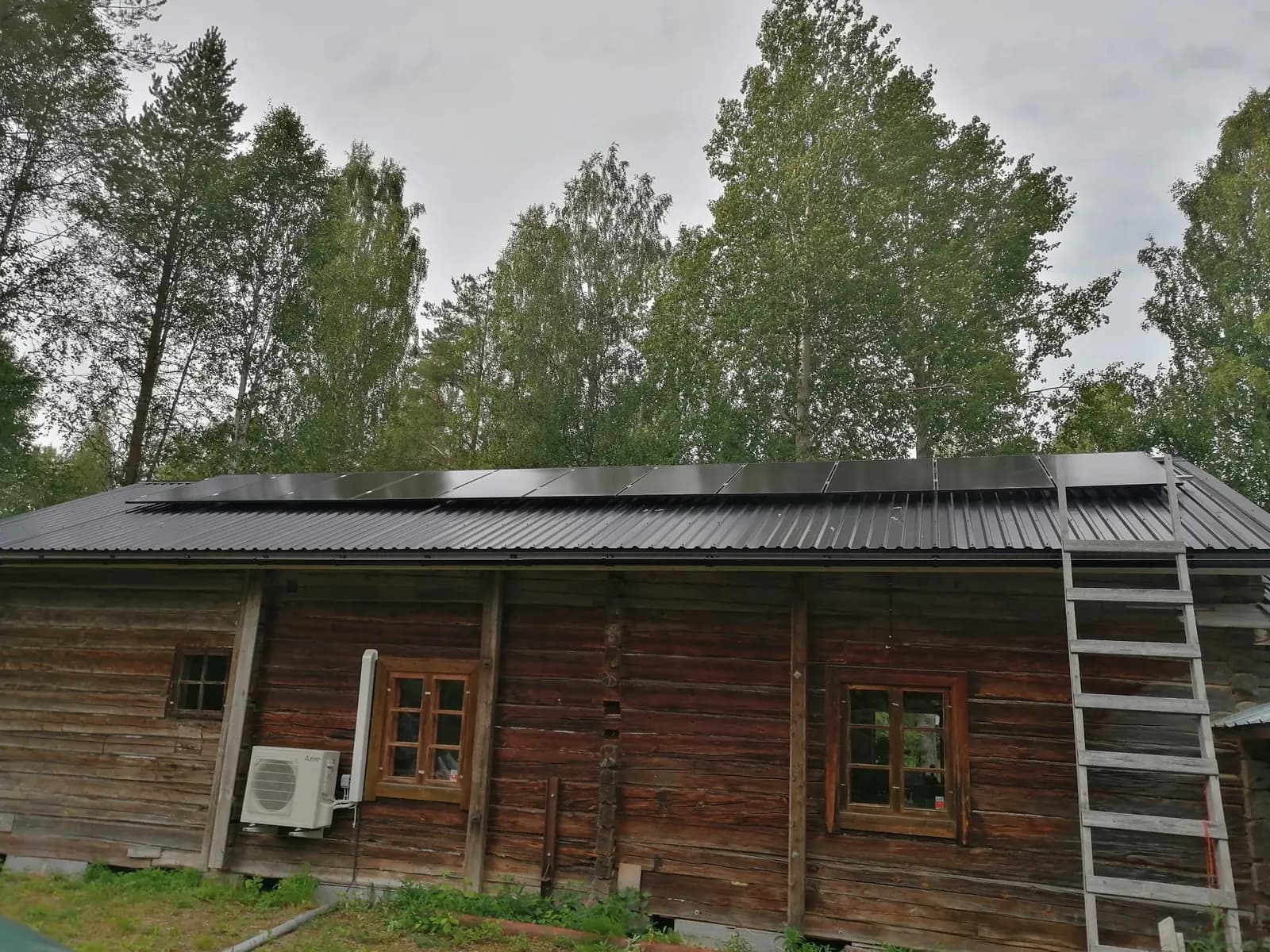 Solar panels on the sheet-metal roof of an old log building
