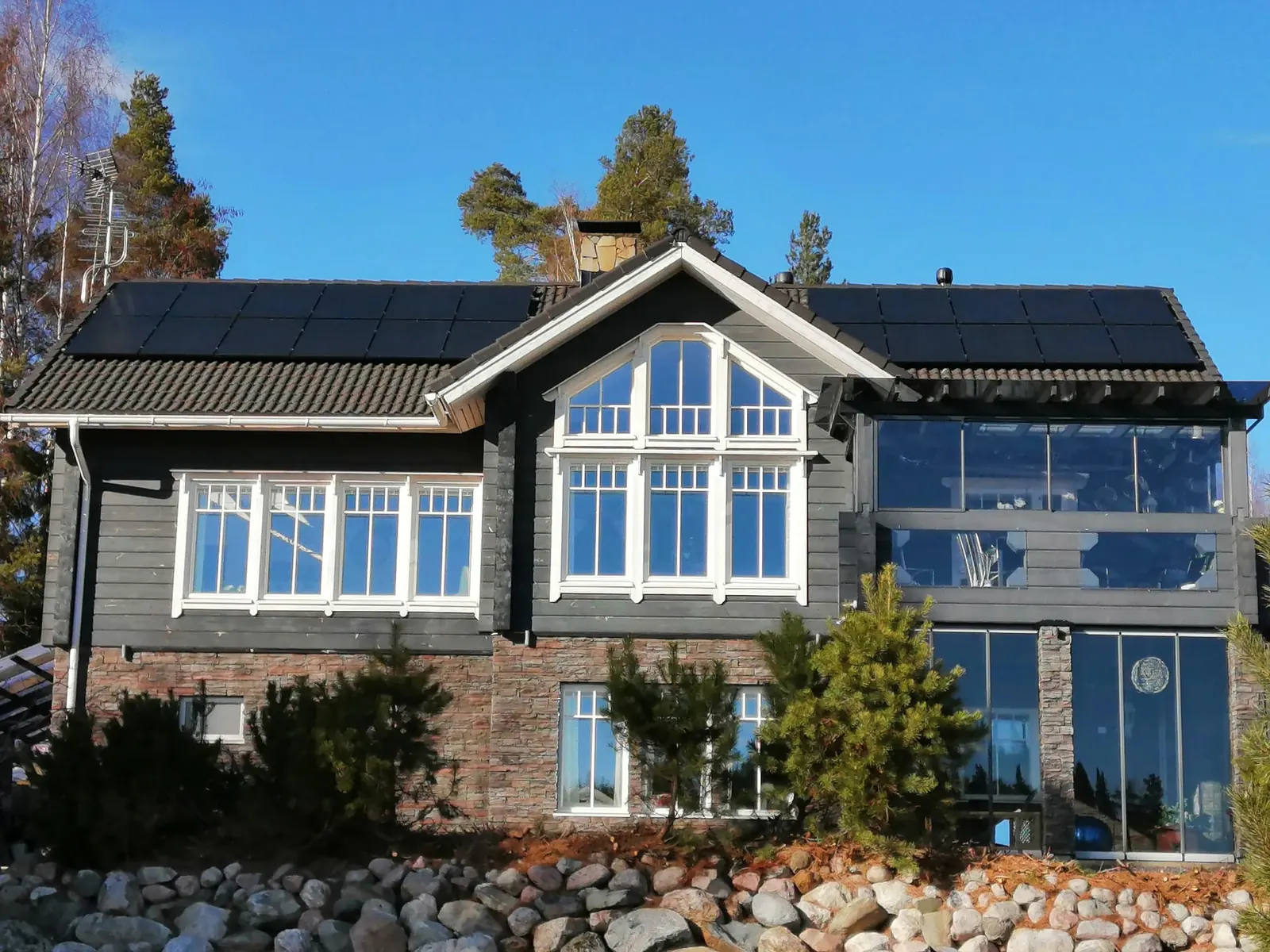 Solar panels on the roof of a dark log house on a clear winter day